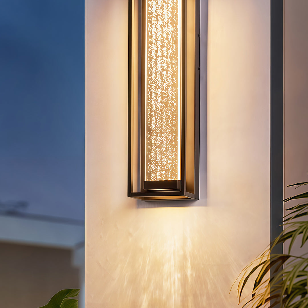 Outdoor sconces black with a textured glass panel, installed on a white wall for a contemporary look.