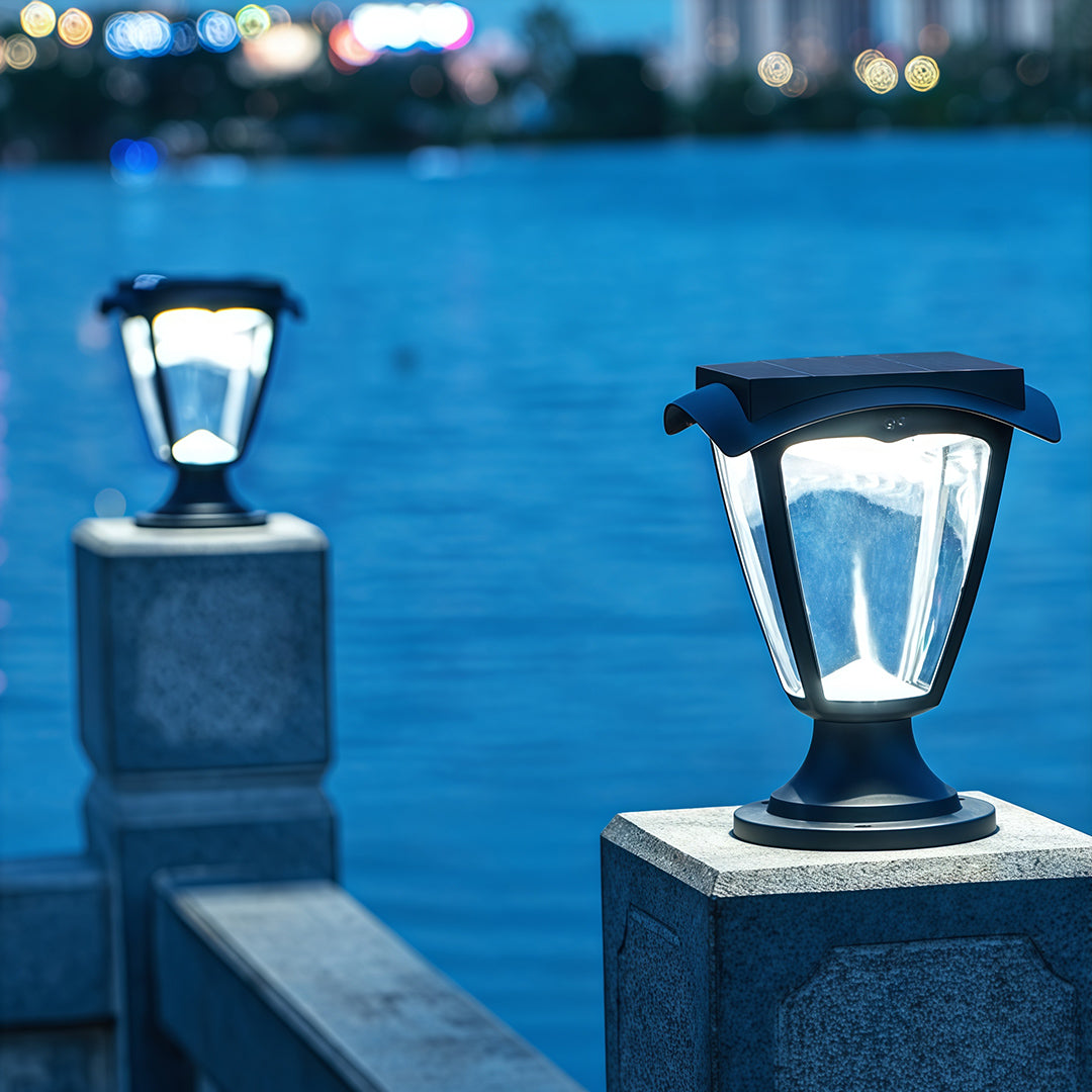 Cool-toned solar light pillar lanterns glowing at dusk on posts along a waterfront railing.