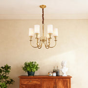 Modern luxury chandeliers above wooden console with greenery in warm interior setting
