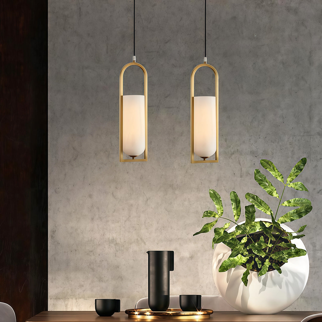 Pair of copper hanging pendant lights over dining area with matching brass finish and minimalist design