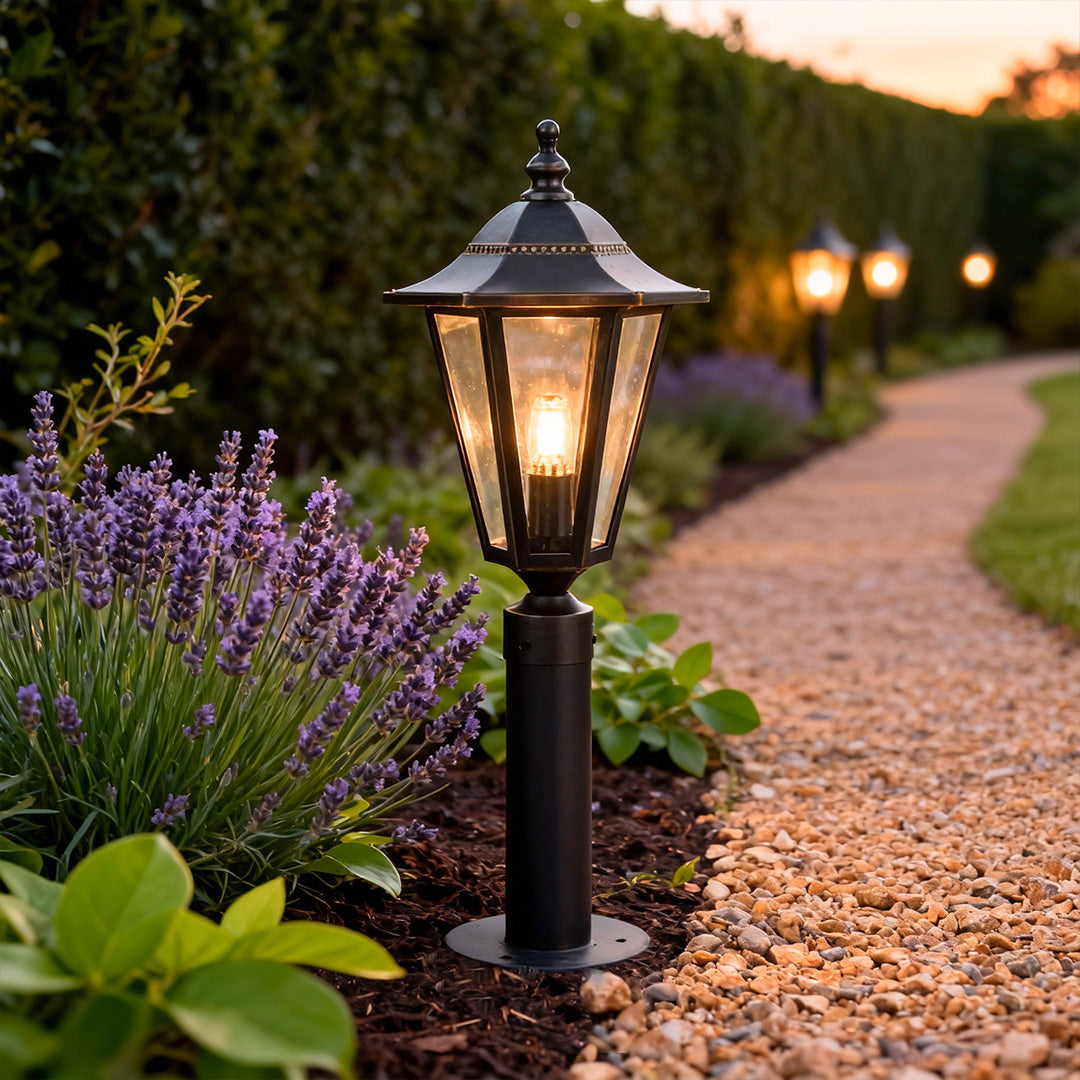 Copper landscape path lights lining a curved gravel path, creating a warm and inviting outdoor landscape lighting effect.