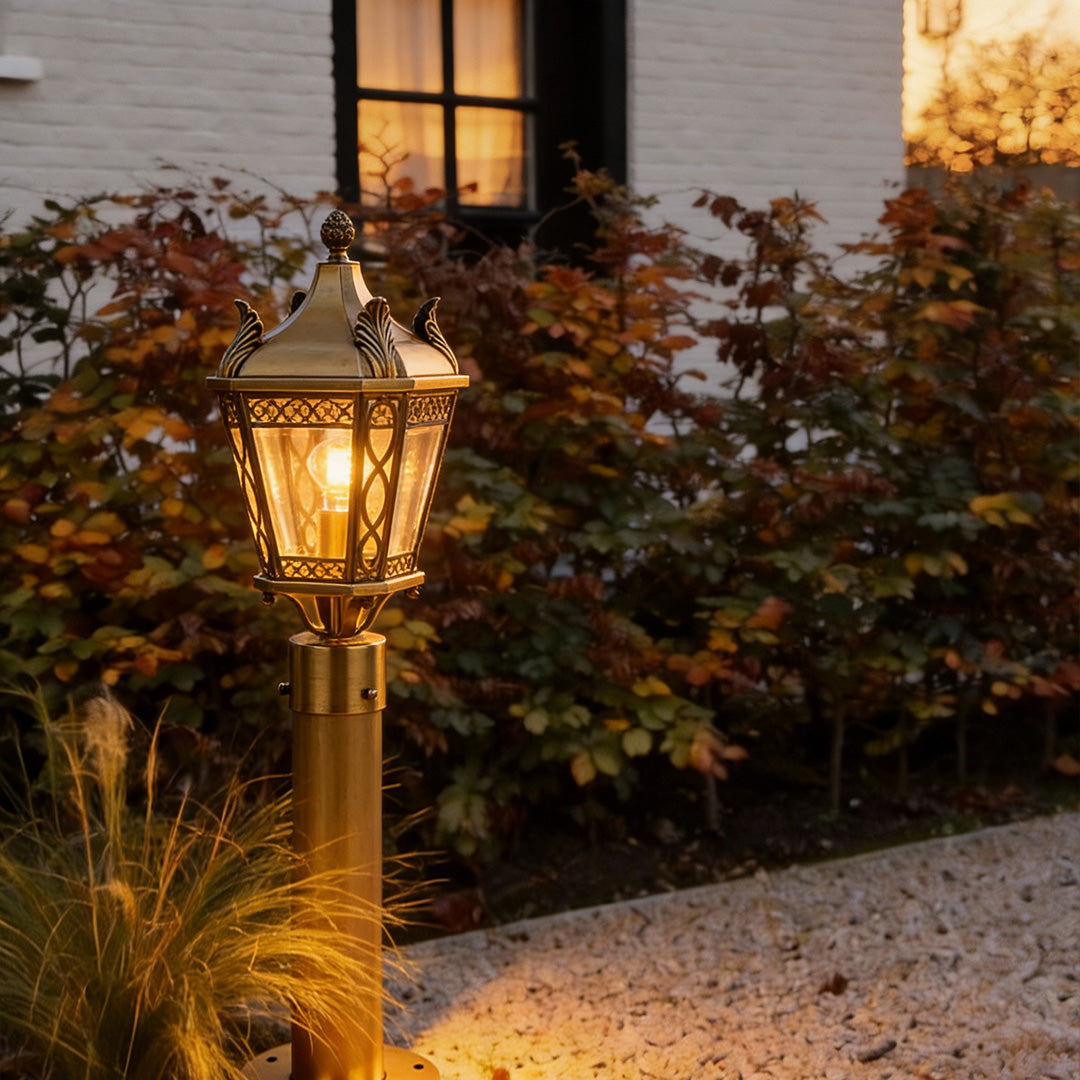 Copper outdoor path lighting fixture glowing warmly beside a house entrance, creating a welcoming outdoor atmosphere.
