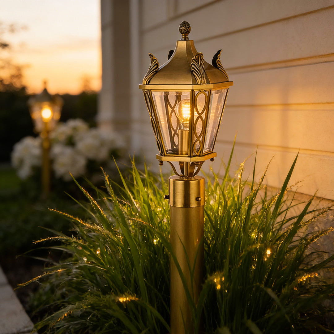 Stylish copper outdoor path lighting at sunset, casting a soft glow on a curved garden walkway and lush greenery.