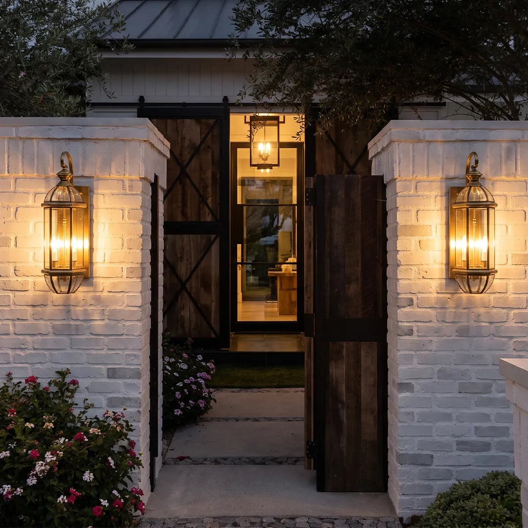 Copper outdoor wall sconce flanking a brick entryway, showcasing a classic lantern shape with warm ambient illumination.