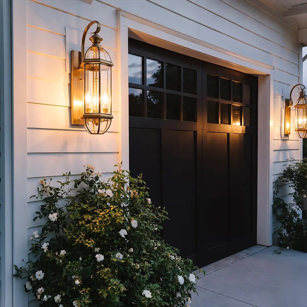 Copper outdoor wall sconces mounted beside a garage door on white siding, adding warm exterior light.