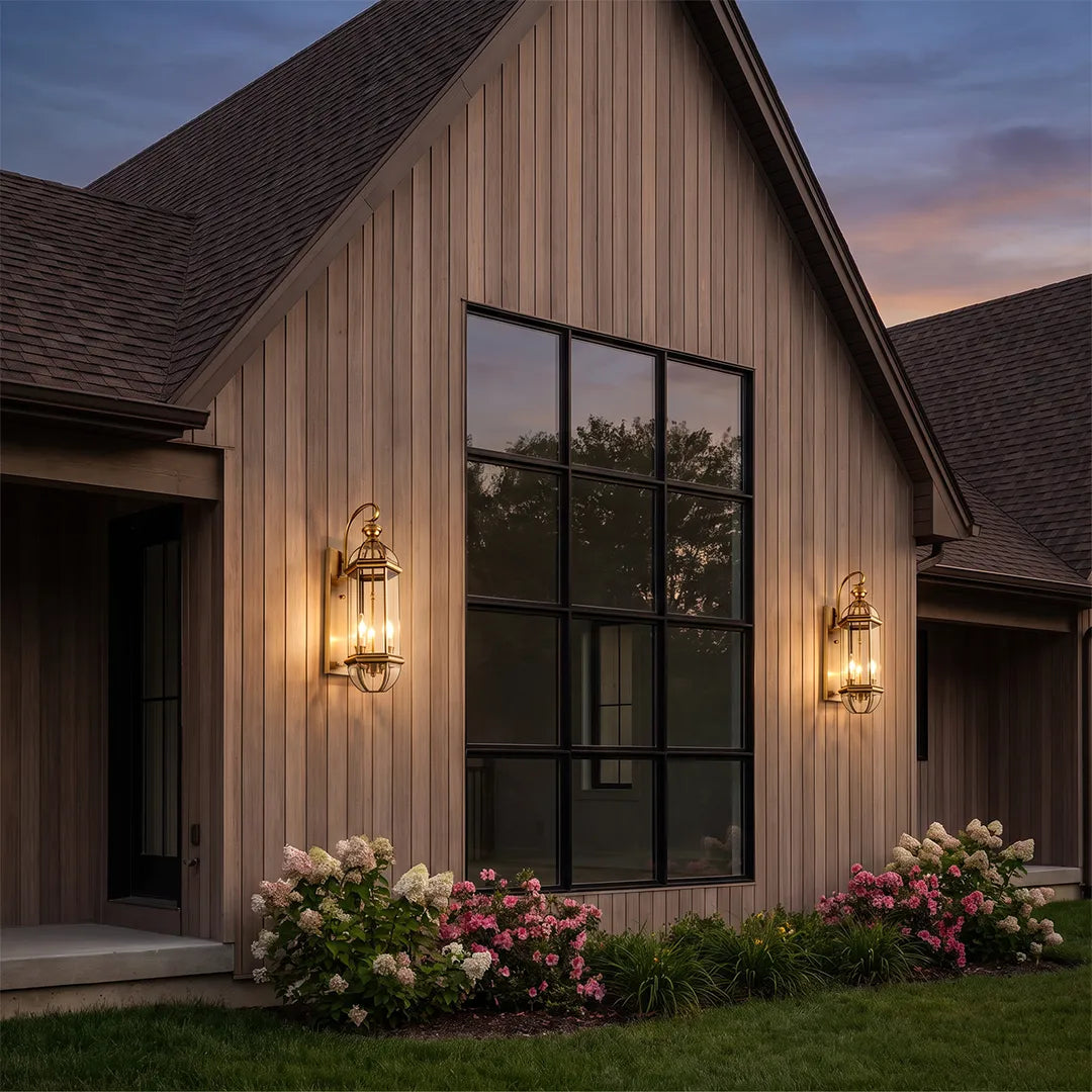 Copper outdoor wall sconce installed on vertical wood siding, adding warm accent lighting beside a large black-framed window.