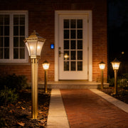 Copper path lights lining a straight front walkway near a house entrance, enhancing visibility and elegant landscape lighting.