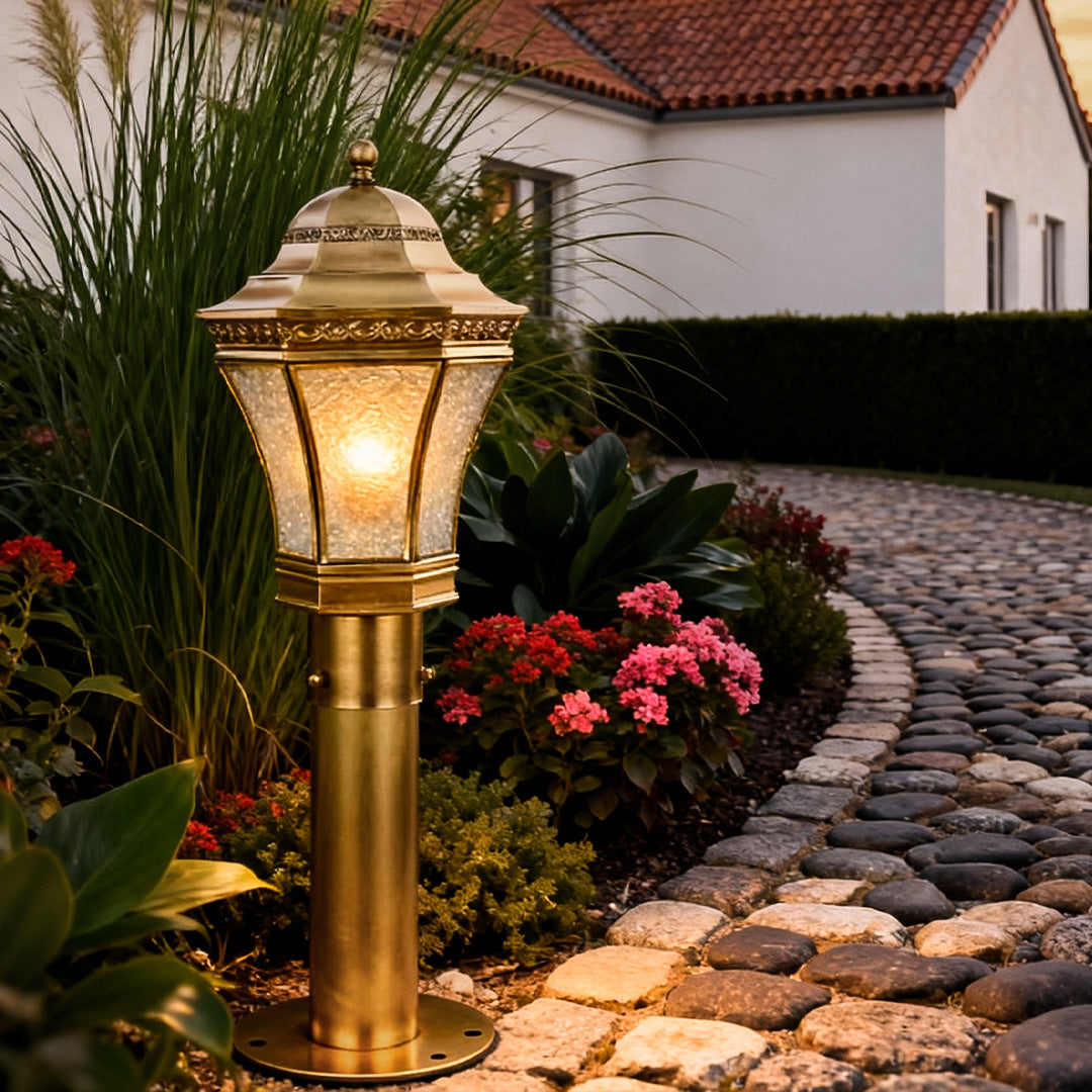 Copper path lights placed beside flowers and stone edging, creating a warm and inviting garden path at night.