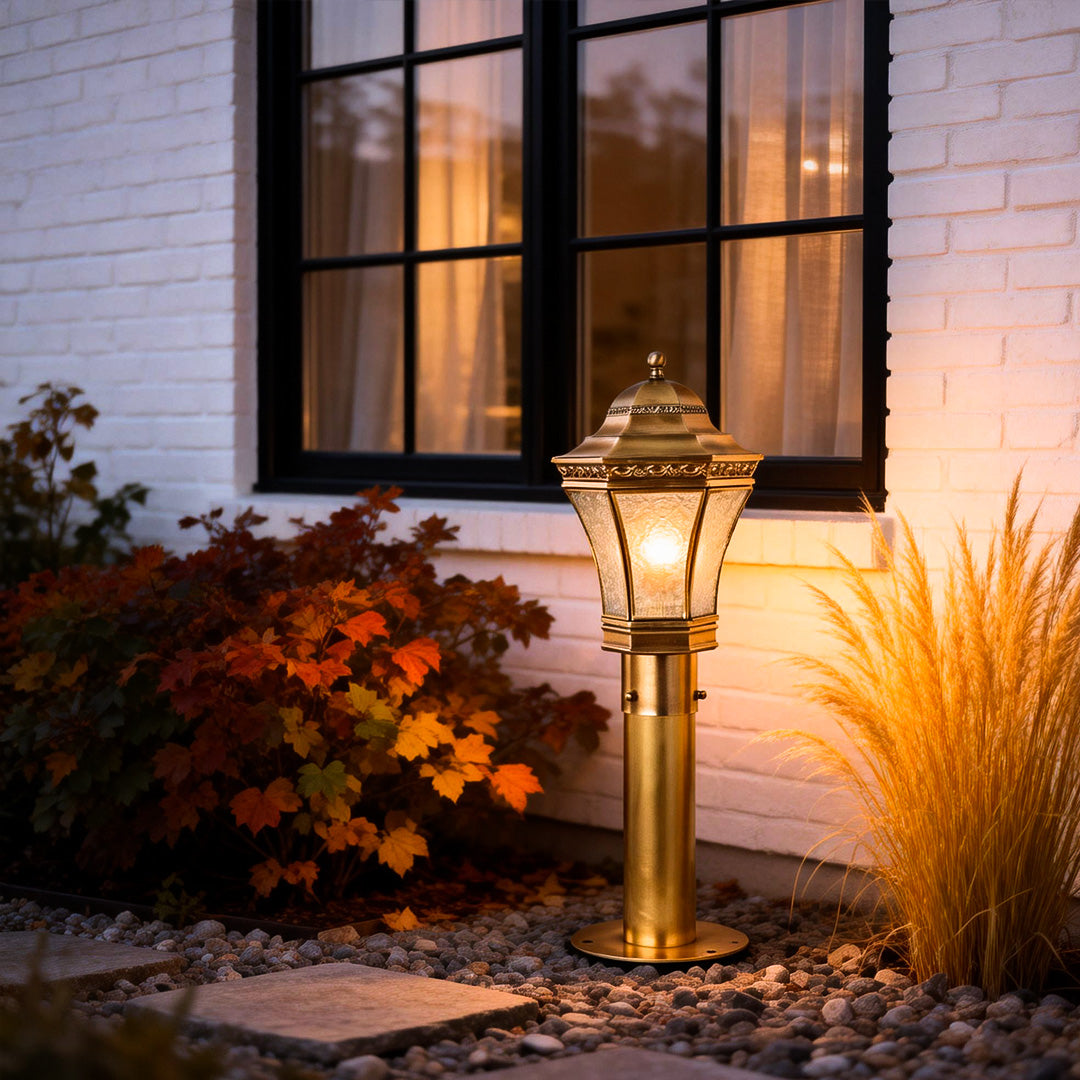Copper path lights illuminating a landscaped area near a window, adding decorative and functional outdoor lighting.