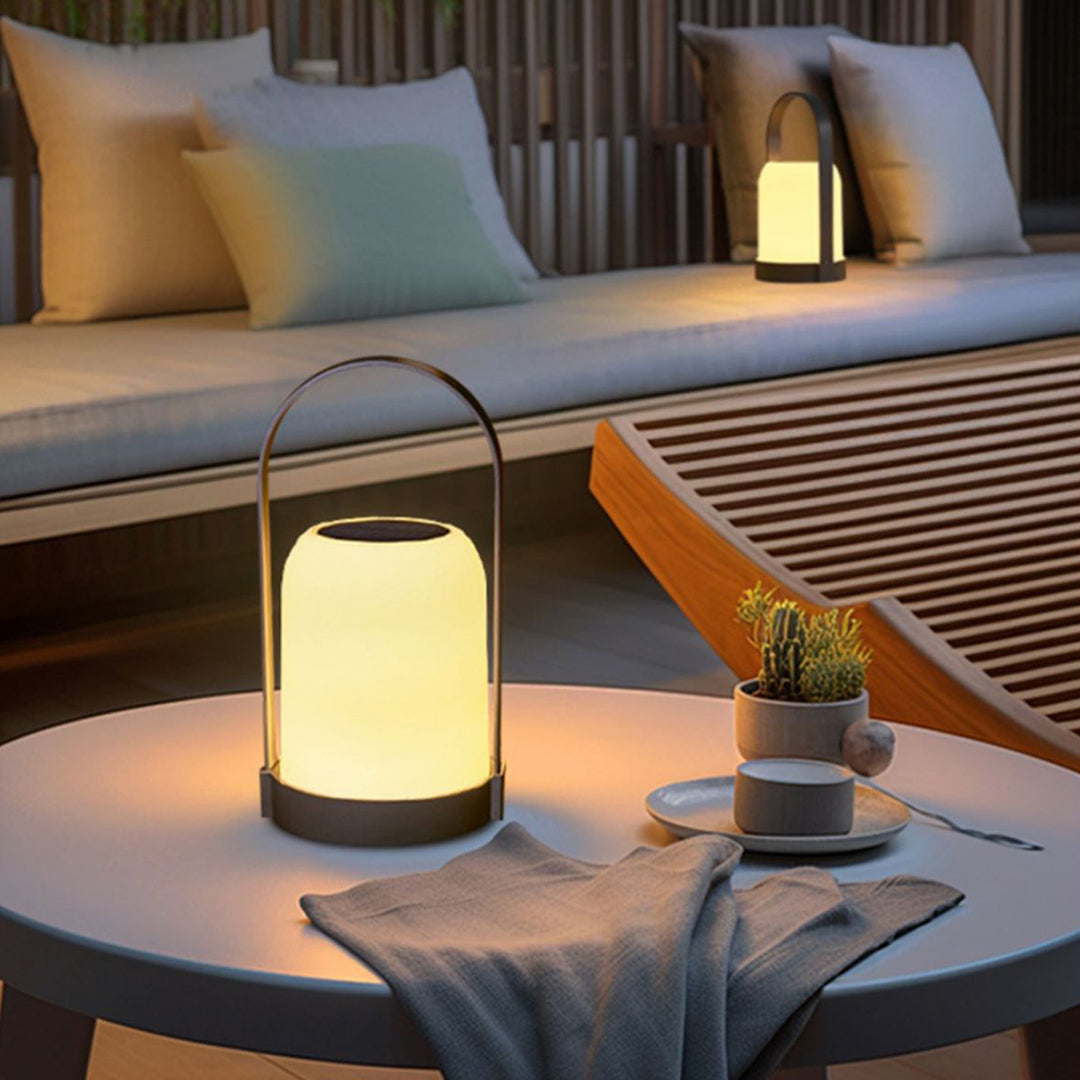 Modern cordless lamp creating warm ambient lighting on outdoor lounge furniture during evening hours