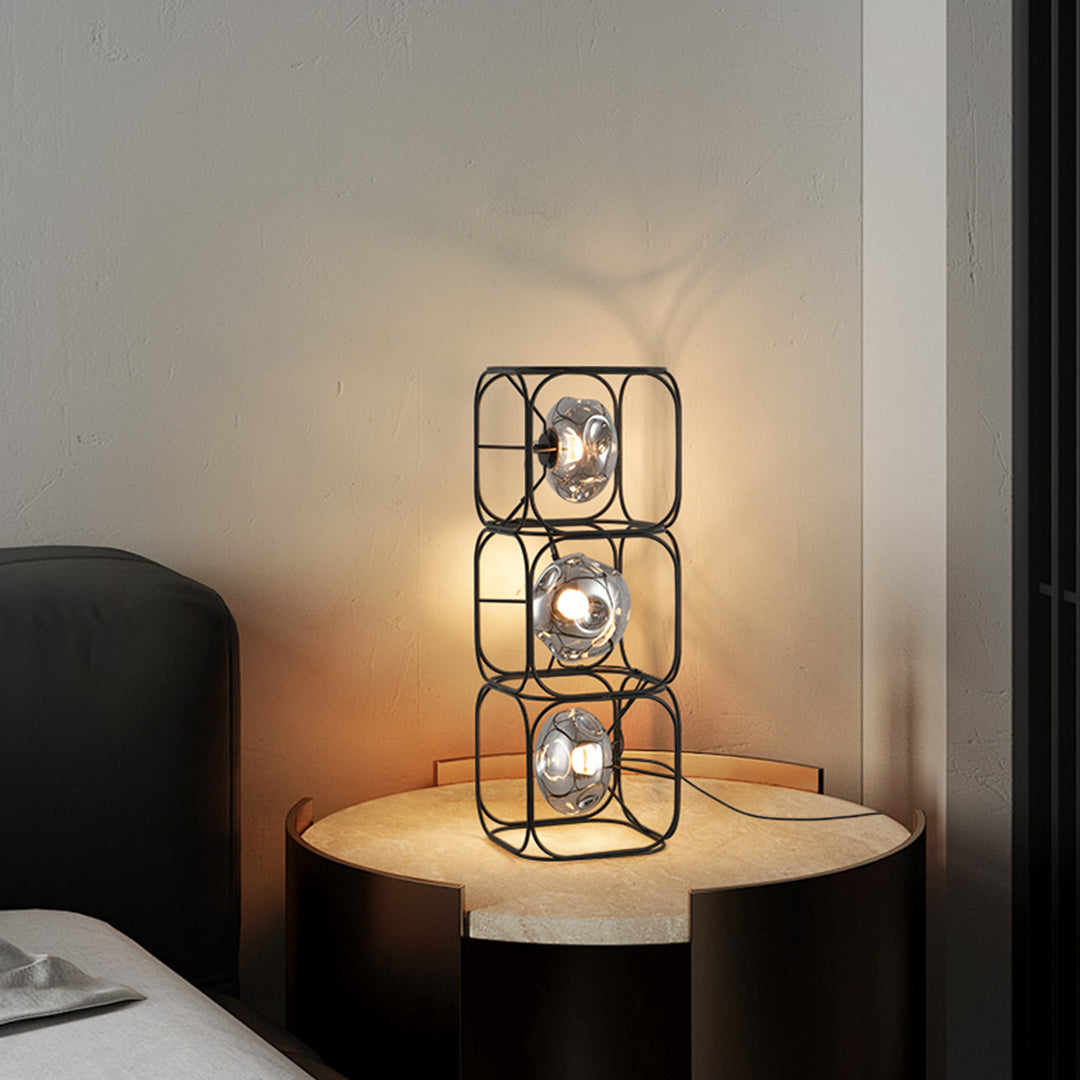 Cube table lamp creating cozy corner lighting with geometric metal frame on wooden surface