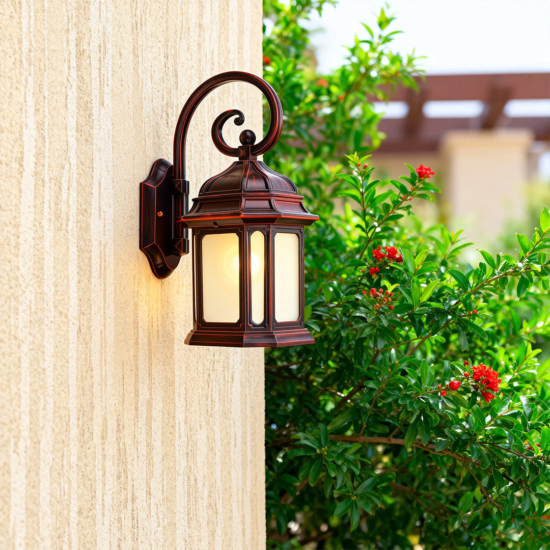 Craftsman exterior LED wall light with frosted glass brightening cream-colored wall near verdant garden