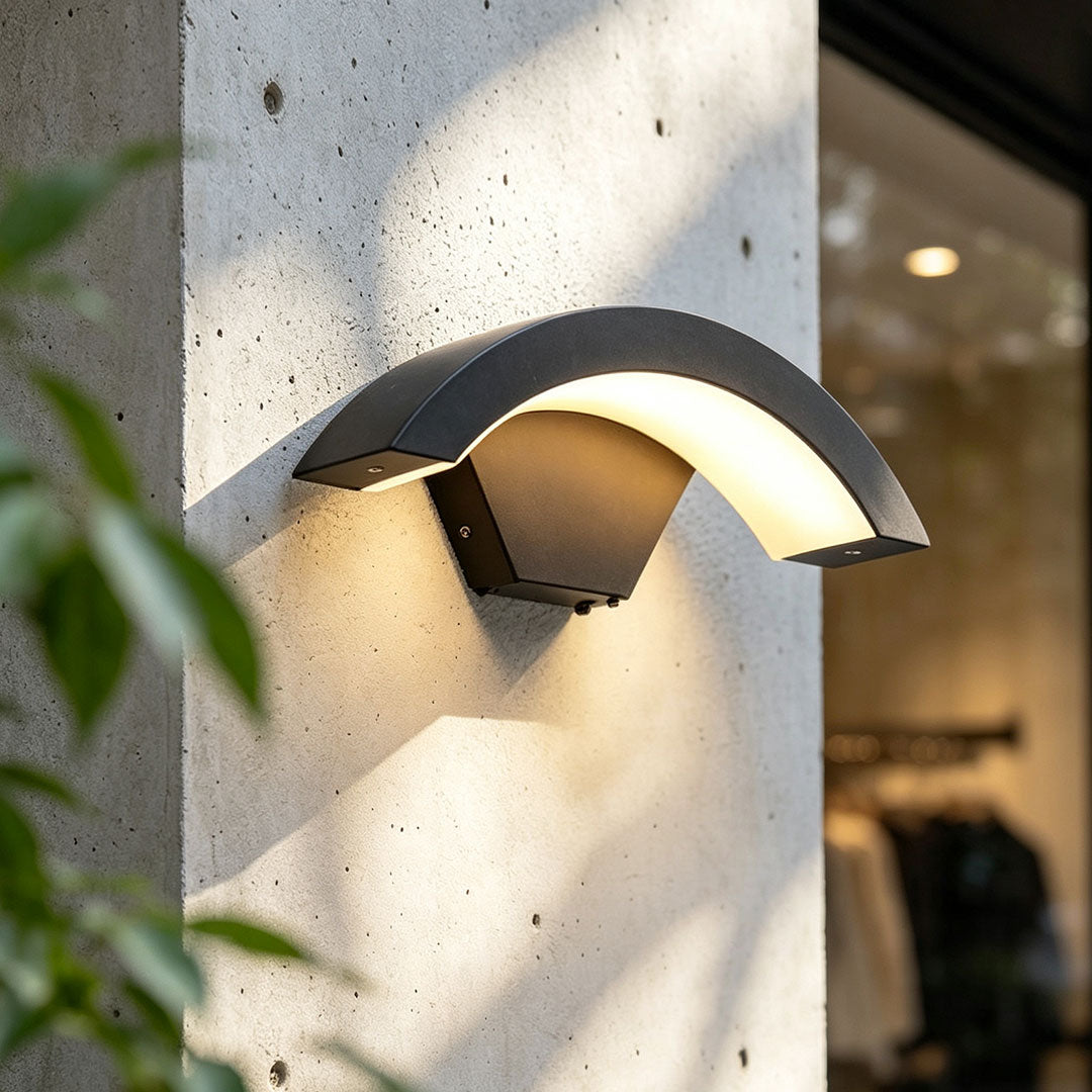 Creative moon curved wall sconce close-up showing the black curved shade and warm downward glow.