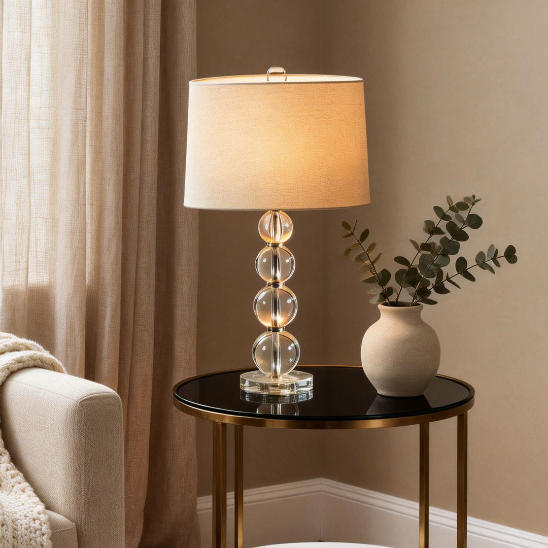 Crystal ball table lamp placed on a round side table beside a sofa.
