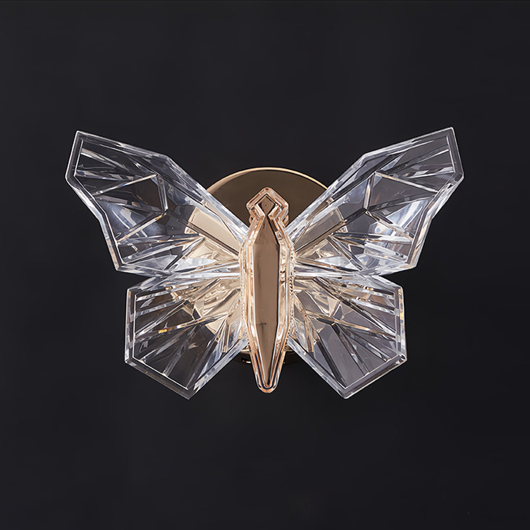 Crystal butterfly wall light with clear translucent wings illuminated against dark background