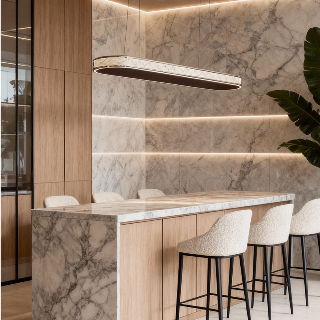 Contemporary crystal linear suspension light installed above a marble kitchen island with wood cabinetry.