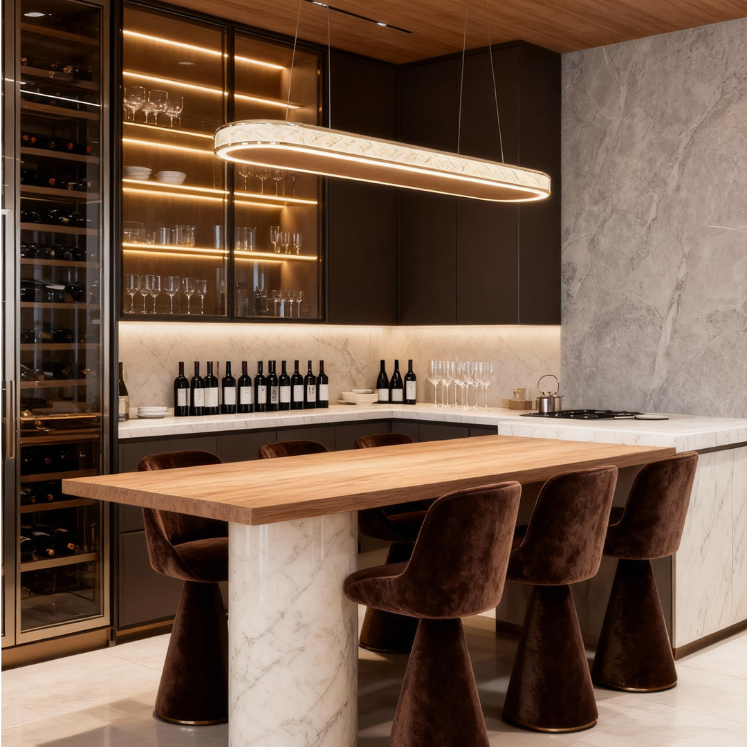 Contemporary crystal linear pendant light illuminating a marble kitchen island with warm metallic tones.