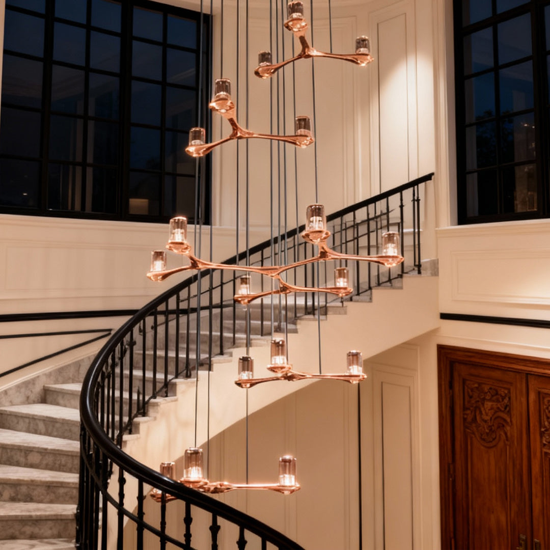 Crystal staircase chandelier creating dramatic lighting effect in grand entryway with sweeping staircase and ornate railings