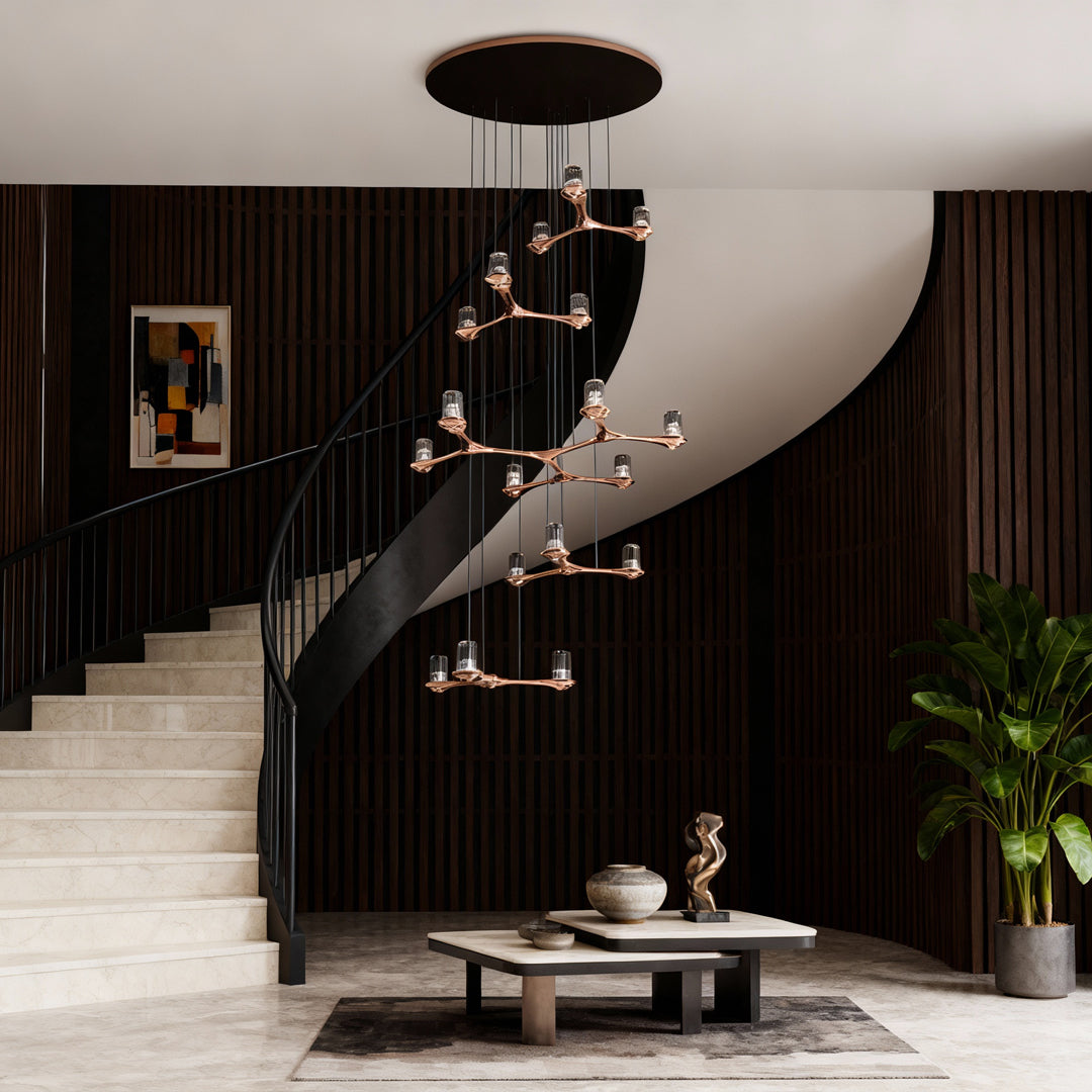 Crystal staircase chandelier providing ambient illumination in luxurious foyer with curved staircase and dark wood accents