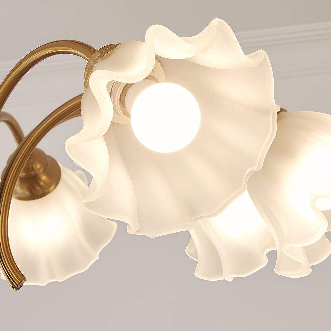 Crystal vintage chandelier with five flower shades suspended above modern kitchen with wood cabinetry and white walls.