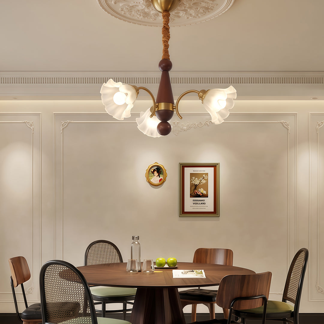 Crystal vintage chandelier with five flower shades suspended above modern kitchen with wood cabinetry and white walls.