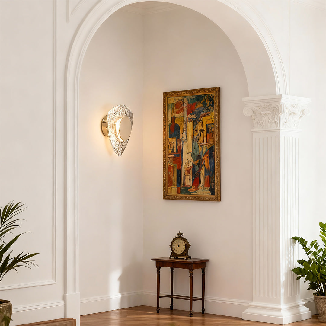 Crystal wall sconce light fixture illuminating arched alcove hallway with religious artwork and classical architectural details