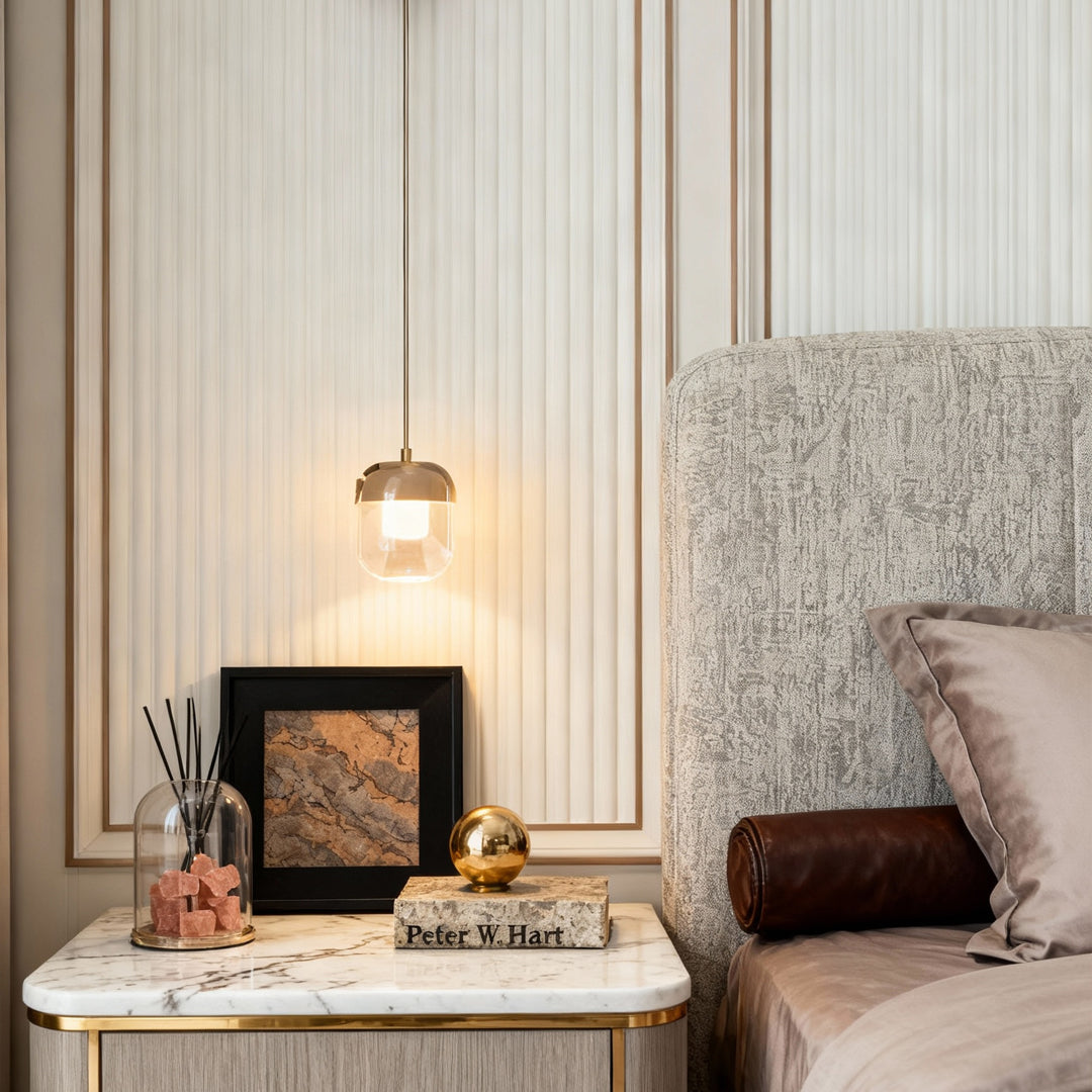 Warm bedside area illuminated by small hanging crystal wall sconce lighting above a nightstand.