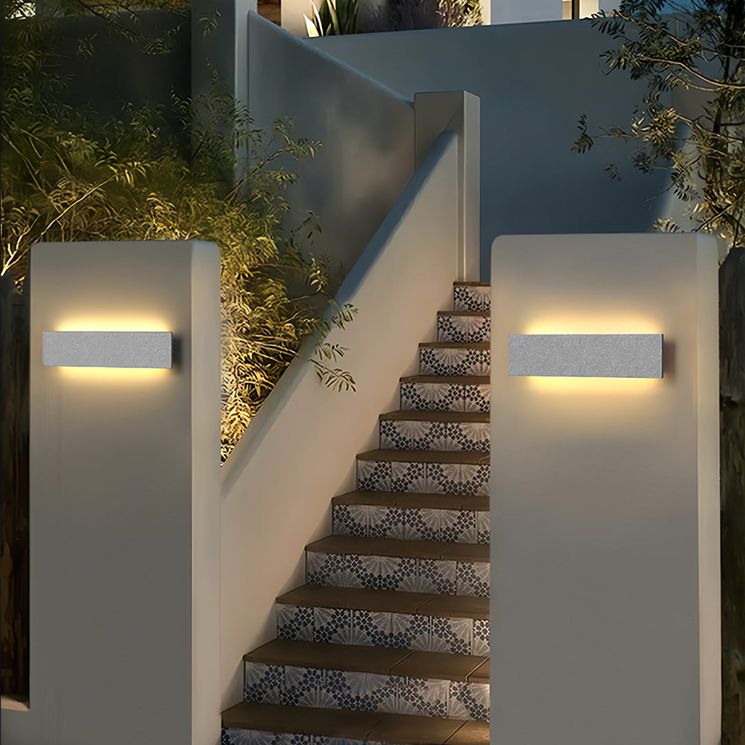 Pathway lined with cube-shaped modern outdoor wall sconces providing layered illumination along stairs.