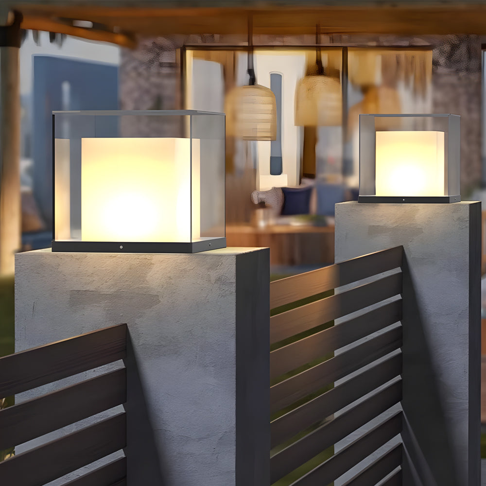Cube-shaped gate pillar light providing warm ambient lighting for an outdoor patio area.