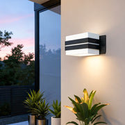 Modern cubic outdoor wall sconce lighting mounted on white exterior wall with warm ambient illumination.