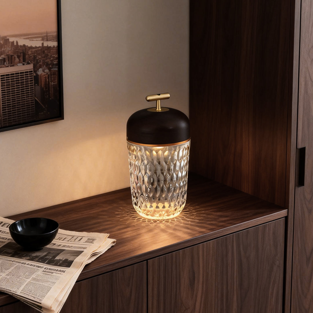 Modern cup glass table lamp with a warm glow, positioned on a wooden nightstand in a bedroom.