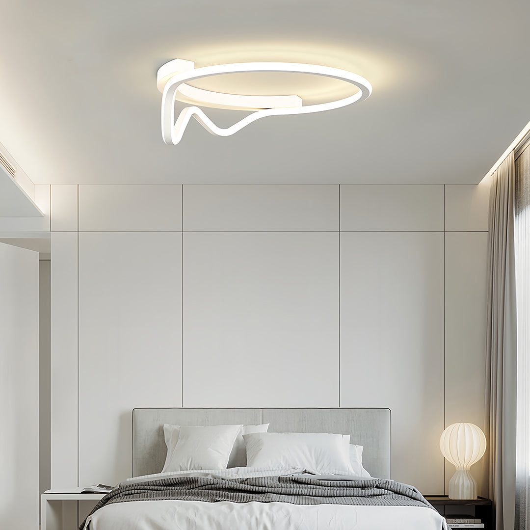 Curved geometric flush mount light with a subtle white ring design, illuminating a contemporary bedroom space with white furniture.