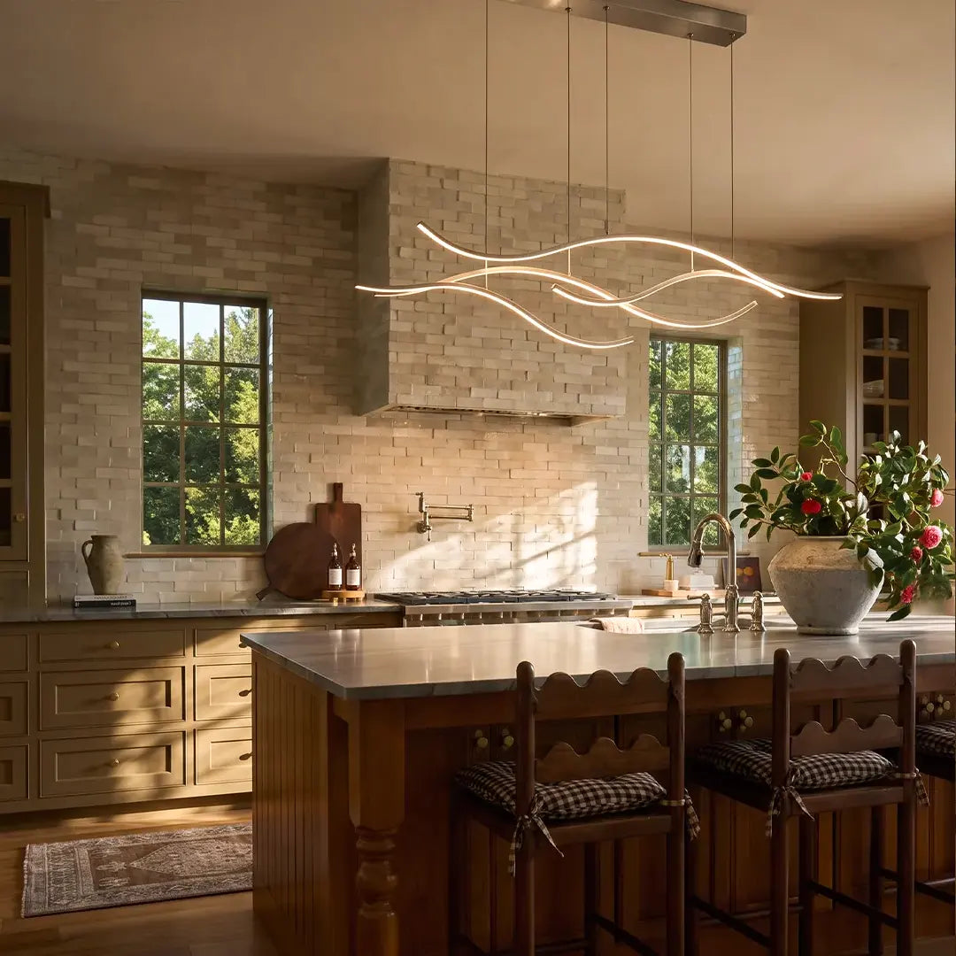 Curved LED pendant light hanging over a rustic kitchen island in a bright space with warm wood cabinetry.