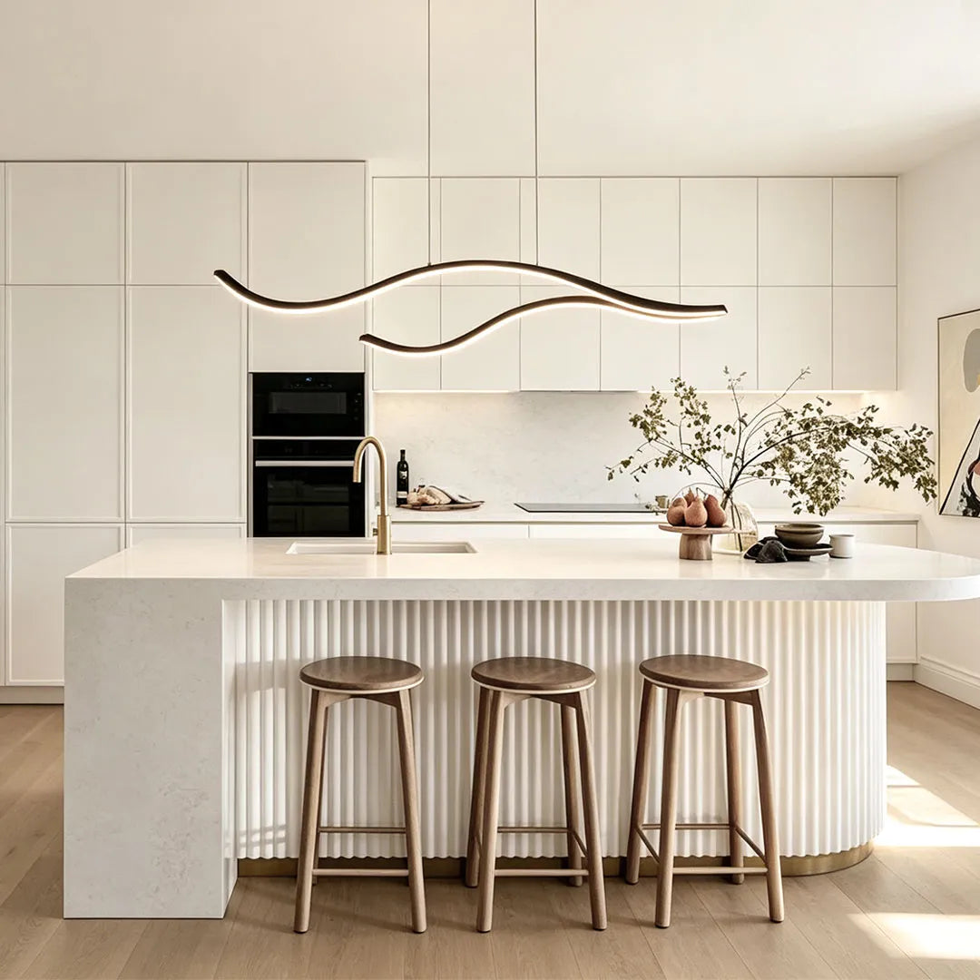 Curved LED pendant light installed above a bright white kitchen island in a minimalist modern interior.