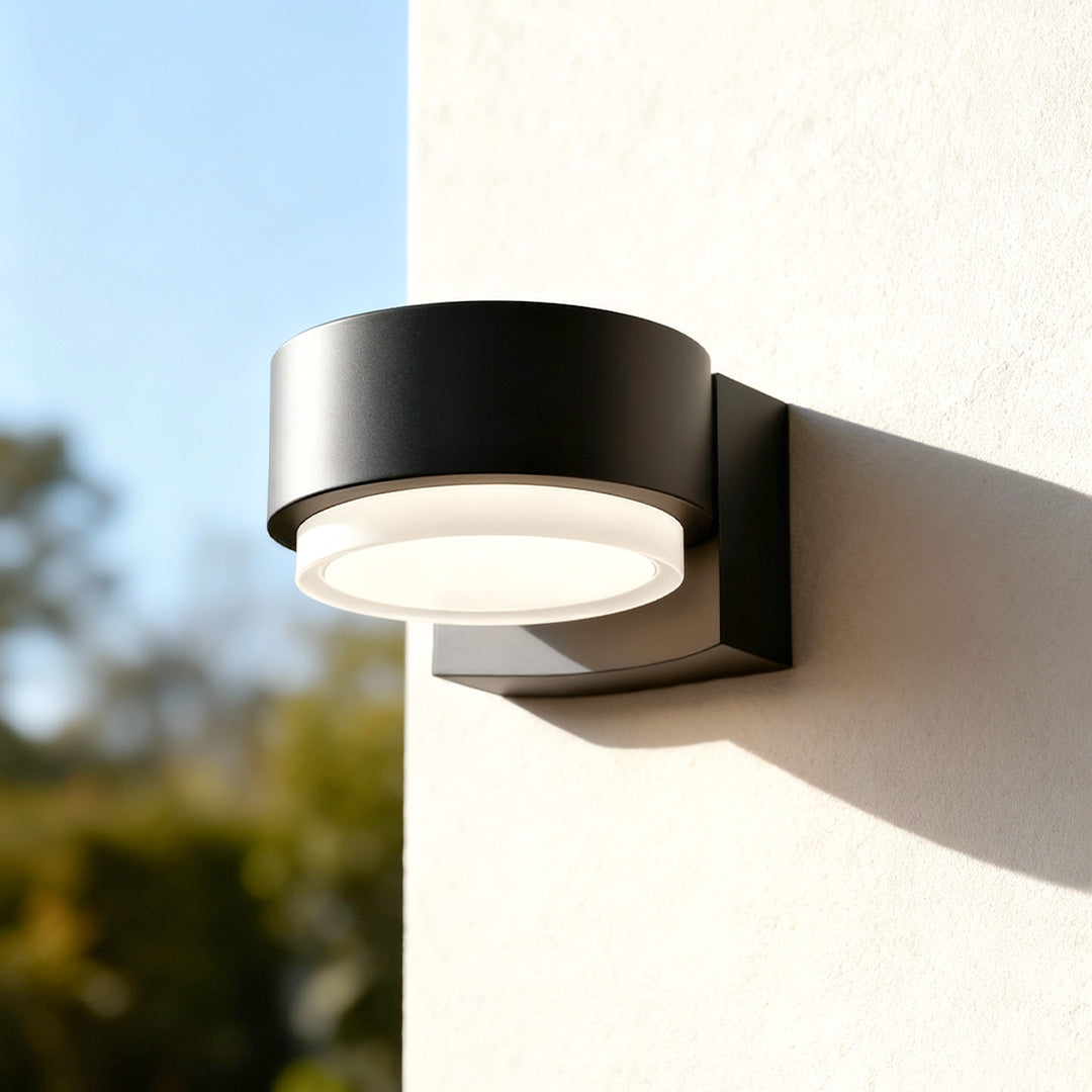 Modern black curved lights for outdoor wall mounted on a bright exterior surface in natural daylight.