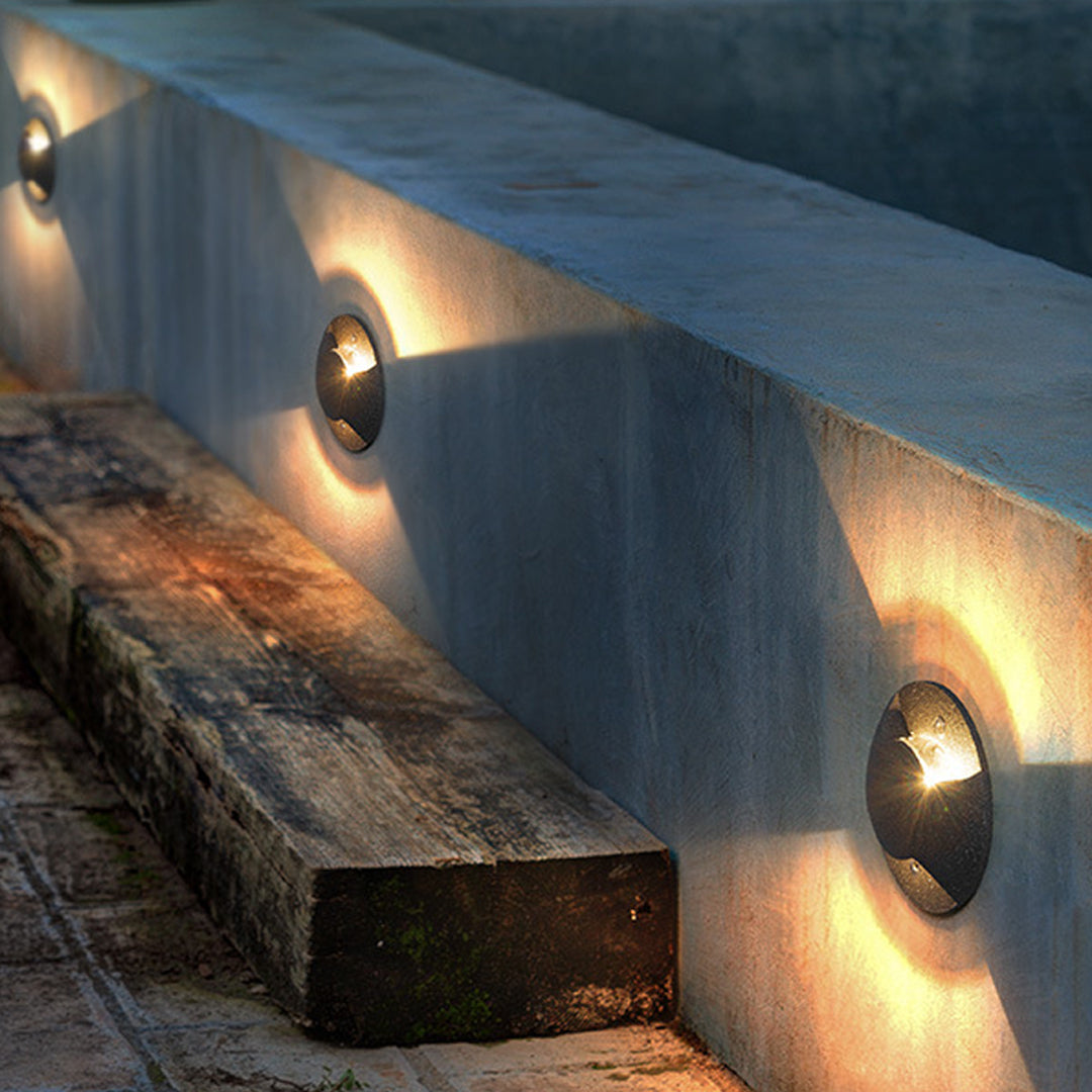 Curved gray outdoor light with flowing organic shape and integrated mounting hardware
