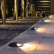 In-ground landscape lights creating dramatic uplighting effects on outdoor pathway at dusk