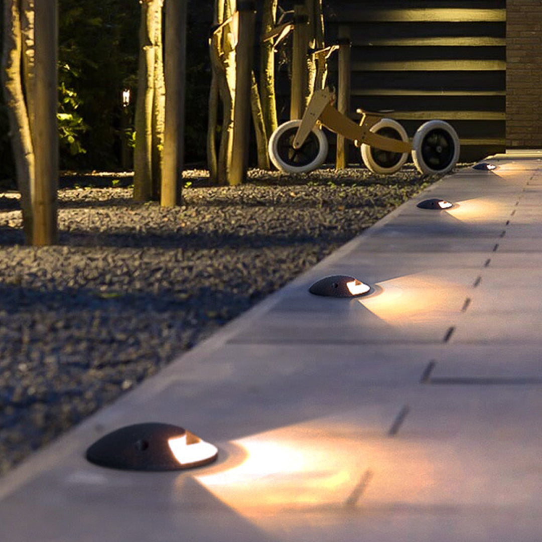 In-ground landscape lights creating dramatic uplighting effects on outdoor pathway at dusk