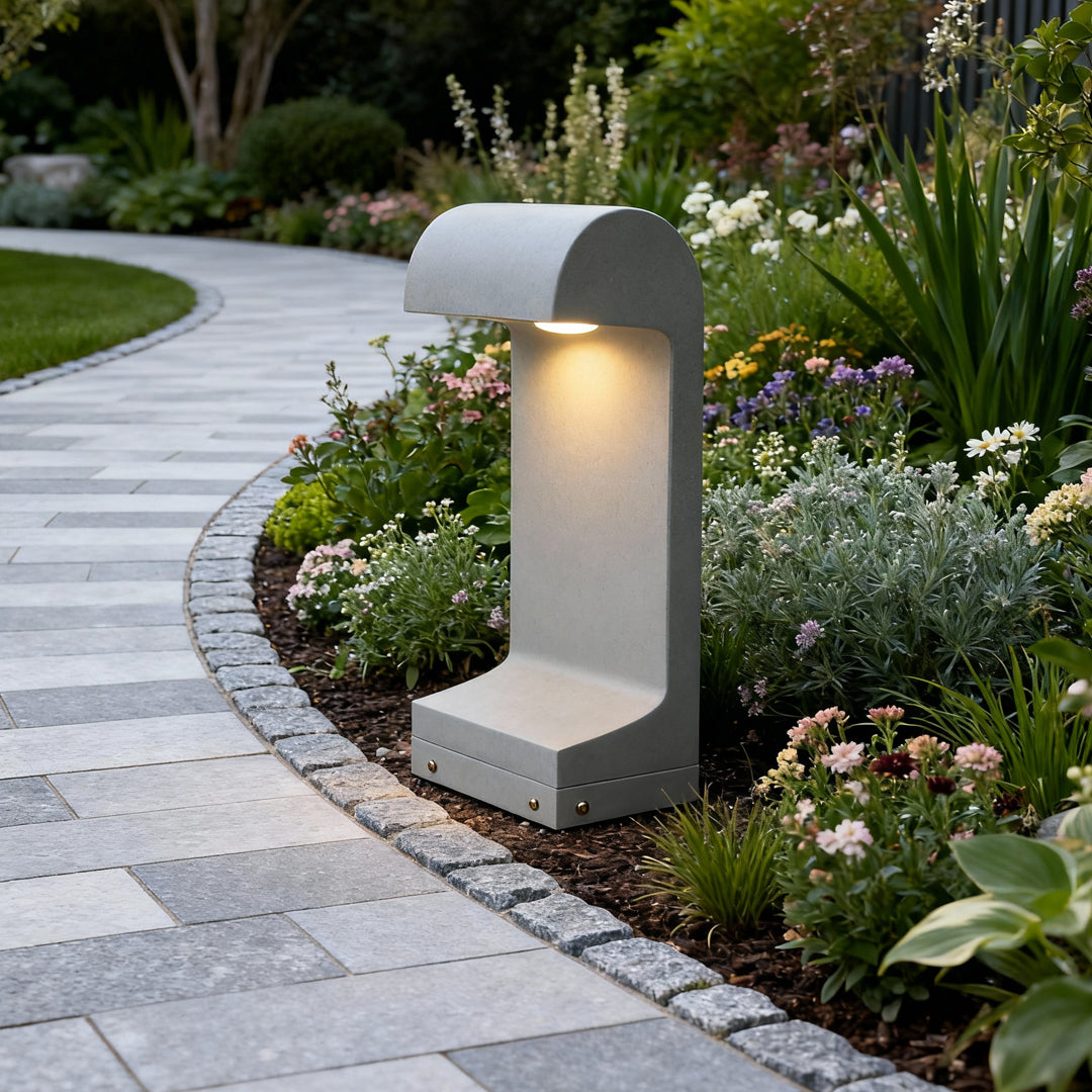 Curved landscape walkway illuminated by warm landscape led lighting from a sculpted outdoor bollard placed along the path.