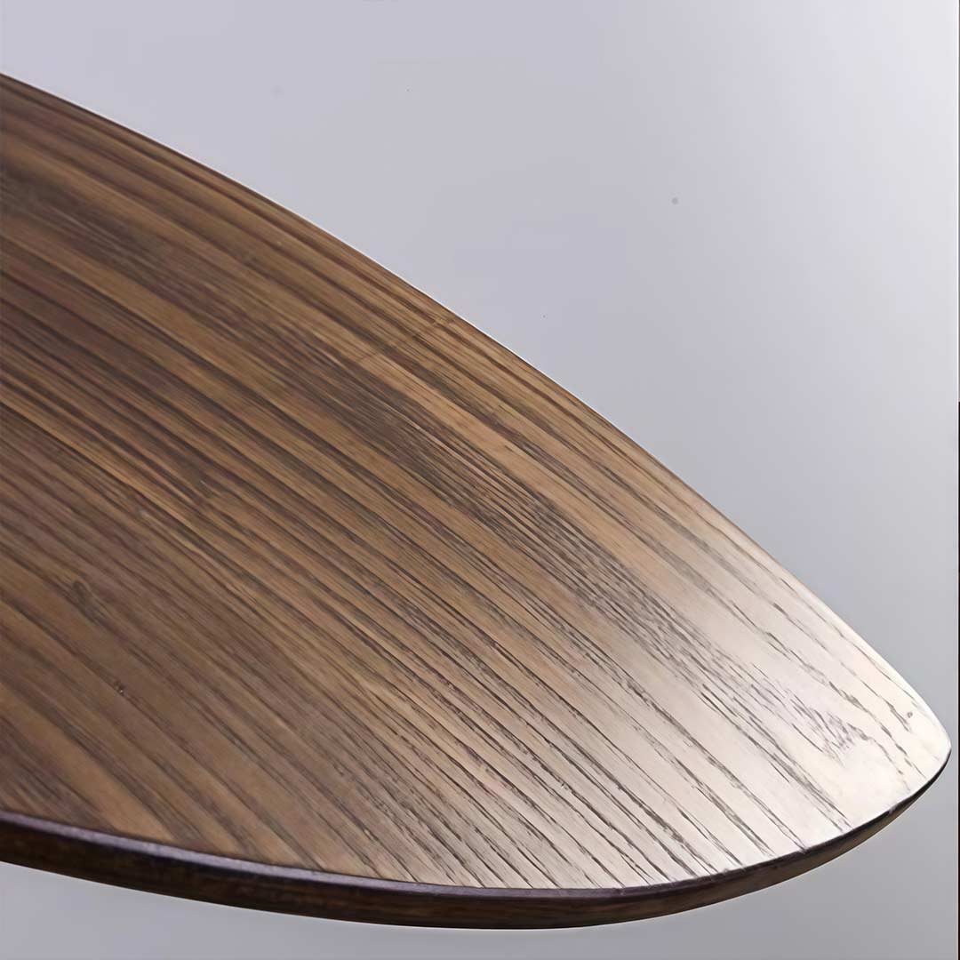 Curved wood pendant light with a minimalist design, hanging above a dining table.