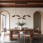 Curved wood pendant light hanging above a rustic wooden dining table in a modern interior.