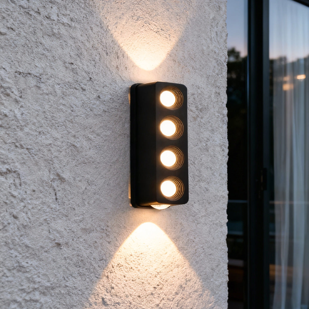 Modern cylindrical unique outdoor wall lighting on a white exterior wall, creating multiple bright focal beams.