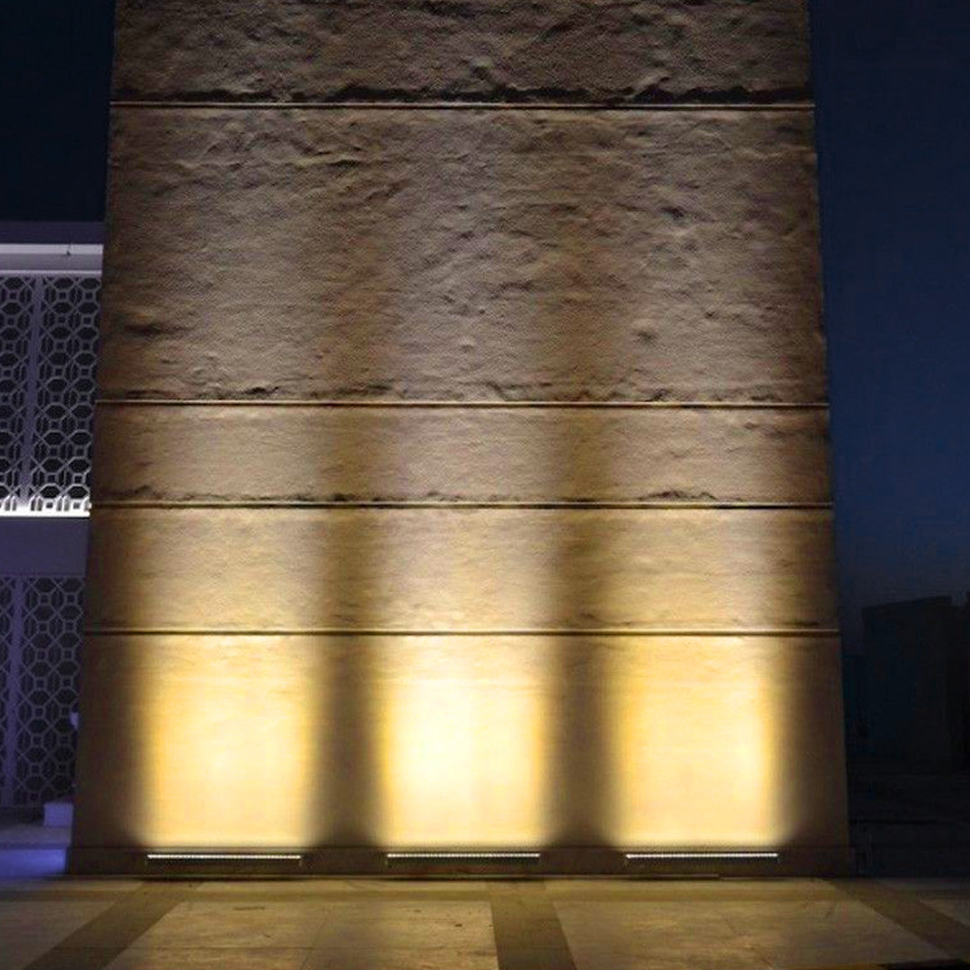 Cylindrical outdoor LED wall wash lighting fixture creating dramatic upward and downward light projection