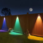 Wooden fence illuminated by colorful RGB LED lights creating vibrant blue, green and orange beams