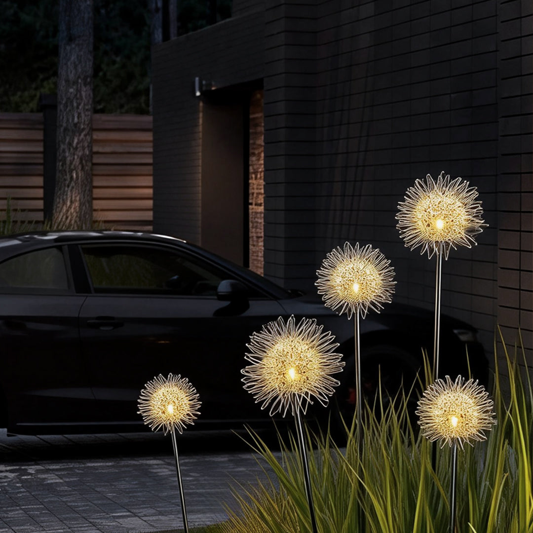 Dandelion landscape lights installed along a driveway, casting a soft glow near a modern building.