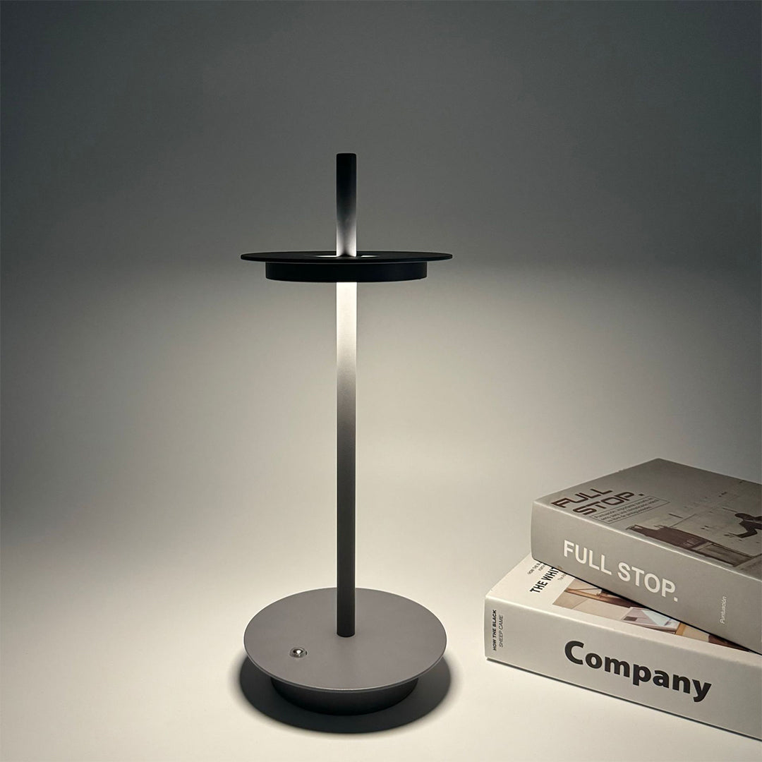 Sleek dimmable table lamp with dark finish creating atmospheric lighting in modern setting