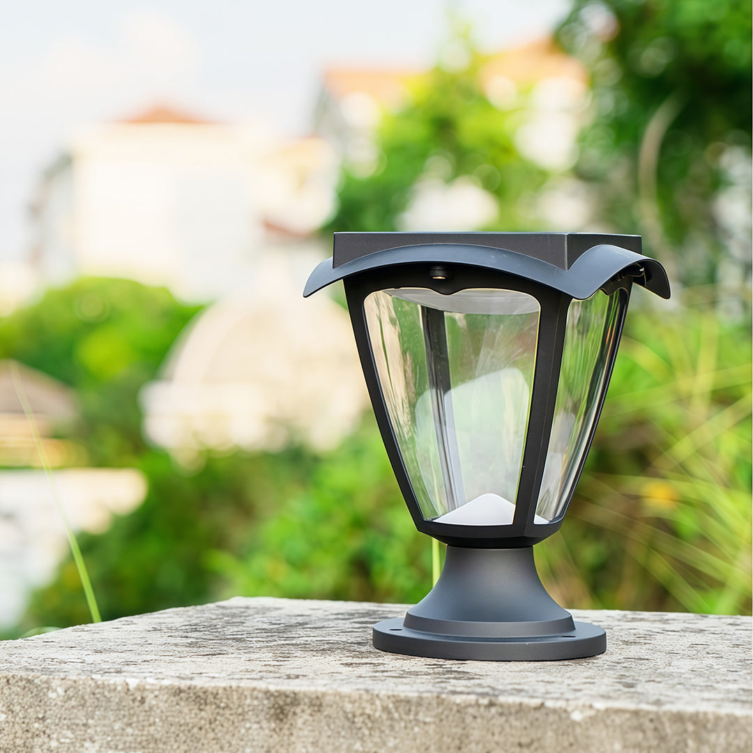 Daytime view of a black solar light pillar lantern showcasing its top-mounted solar panel and classic design.