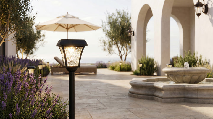 Solar led path lights placed beside stone paving and greenery, offering soft ambient lighting for residential landscape design.