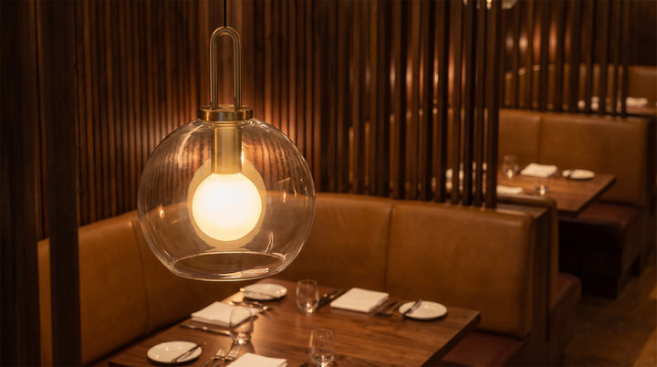 Elegant frosted glass mini pendant lights with gold U-loop hardware in a luxury marble kitchen.