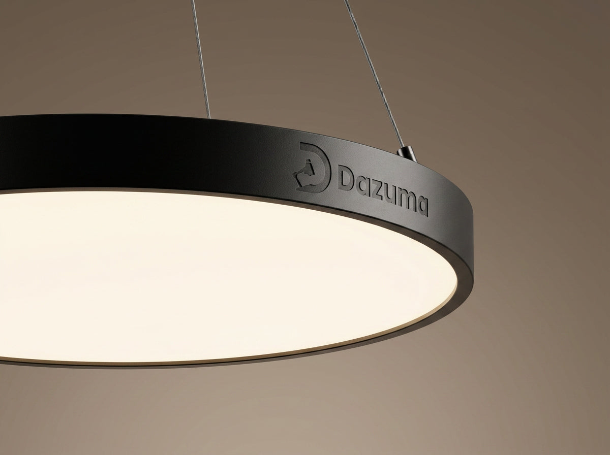 Close-up of a modern circular black pendant lights fixture by Dazuma with a sleek frosted diffuser emitting warm light.
